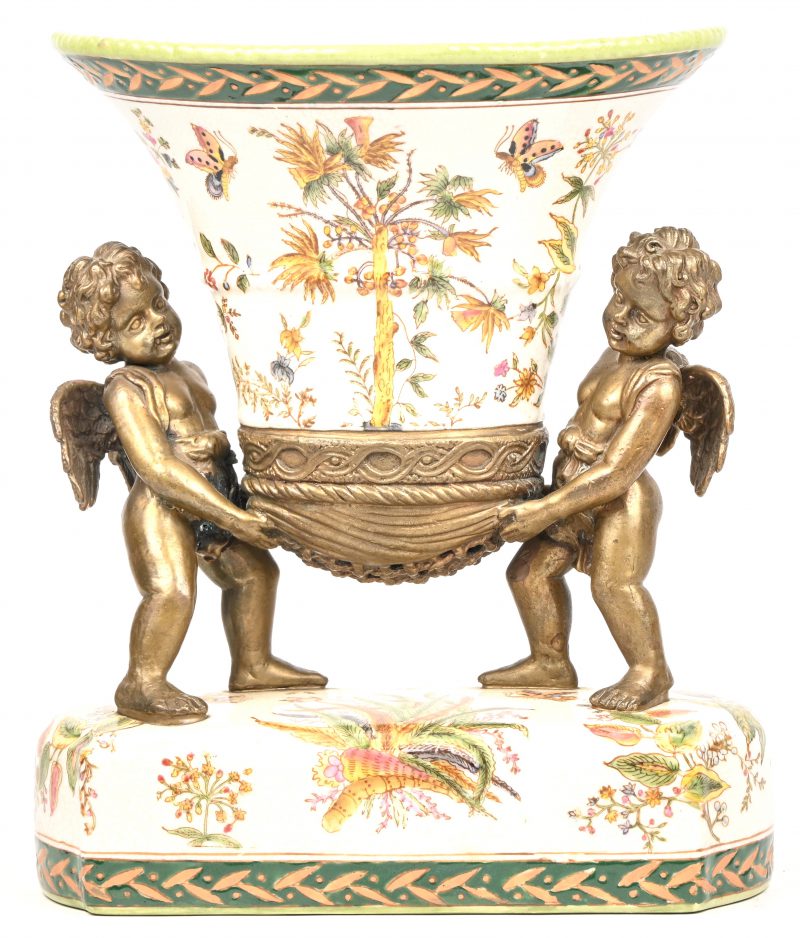 Een porseleinen vaas met floraal decor, gedragen door 2 bronskleurige Cherubijnen.