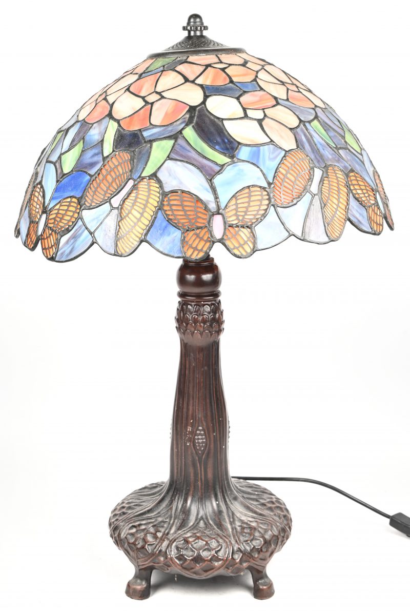 Een lamp in Tiffany-stijl met bronskleurige voet en glas in lood kap met vlinders in het decor.