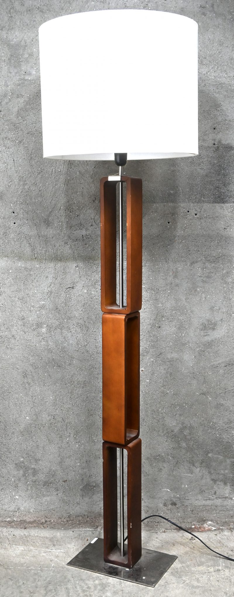 Een design houten vloerlamp in geometrisch design op metalen voet.