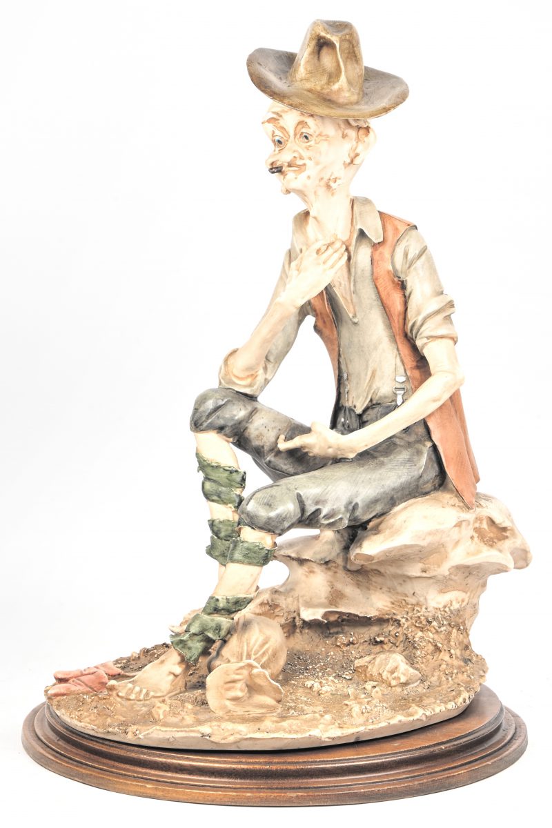 Een kunstoffen beeld op houten voet, verso gemerkt.