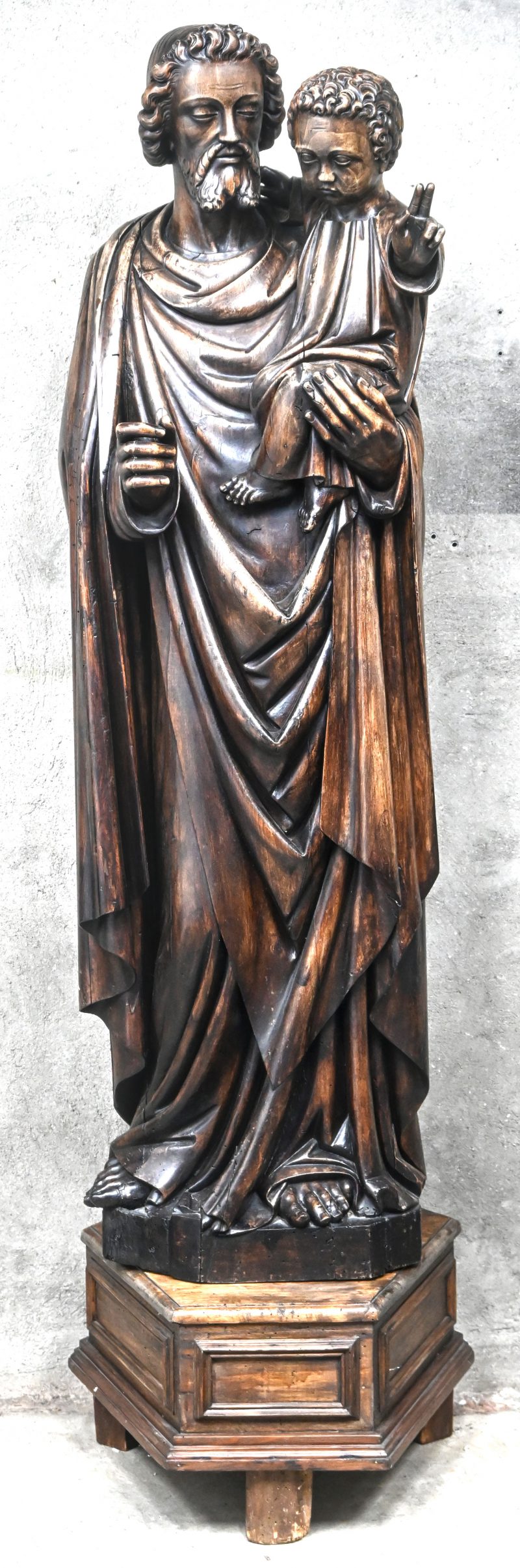 Een polychroom houten gesculpteerd Sint-Antoniusbeeld op houten sokkel.