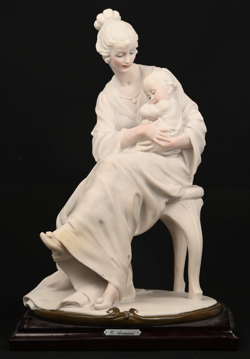“Vrouw met kind”. Een kunstoffen beeldje op houten voet. Onderaan gesigneerd en gelabeld.