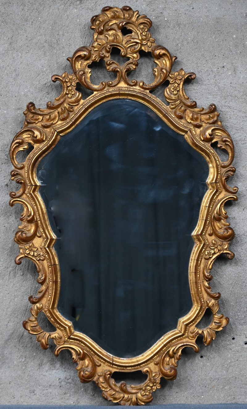 Een geslepen spiegel in vergulde kader naar Barok voorbeeld.