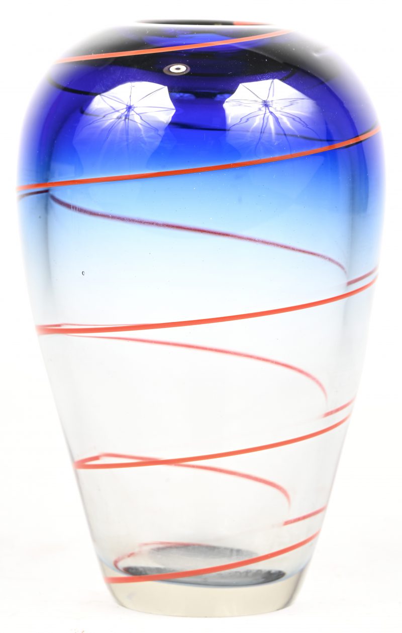 Een disign vaas van blauw wit glas met rode spiraal.