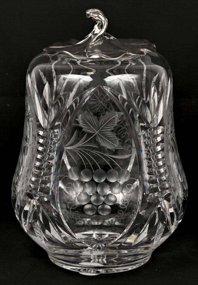 Een kristallen dekselpot met geslepen wijnranken en verzilverd deksel. Randschade aan het kristal.