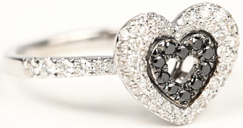Een 18 kt witgouden hartvormige ring bezet met zwarte en witte briljanten met een gezamenlijk gewicht van +- 0,64 ct.