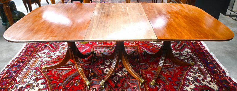 Een Regency D-End tafel bestaande uit drie afzonderlijke bladen met telkens een centrale poot en met twee verlengbladen. Met messingen trekkers.