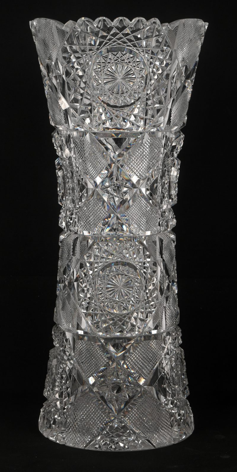 Een gesculpteerd kristalglazen vaas met geometrische patronen. Schilfer en barst onderaan.