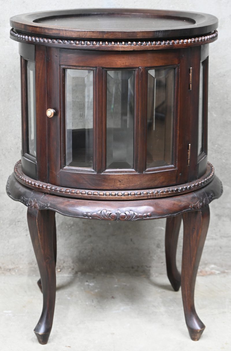 Een rond houten barkastje met gesculpteerde details, 2 deurtjes en geslepen glas.