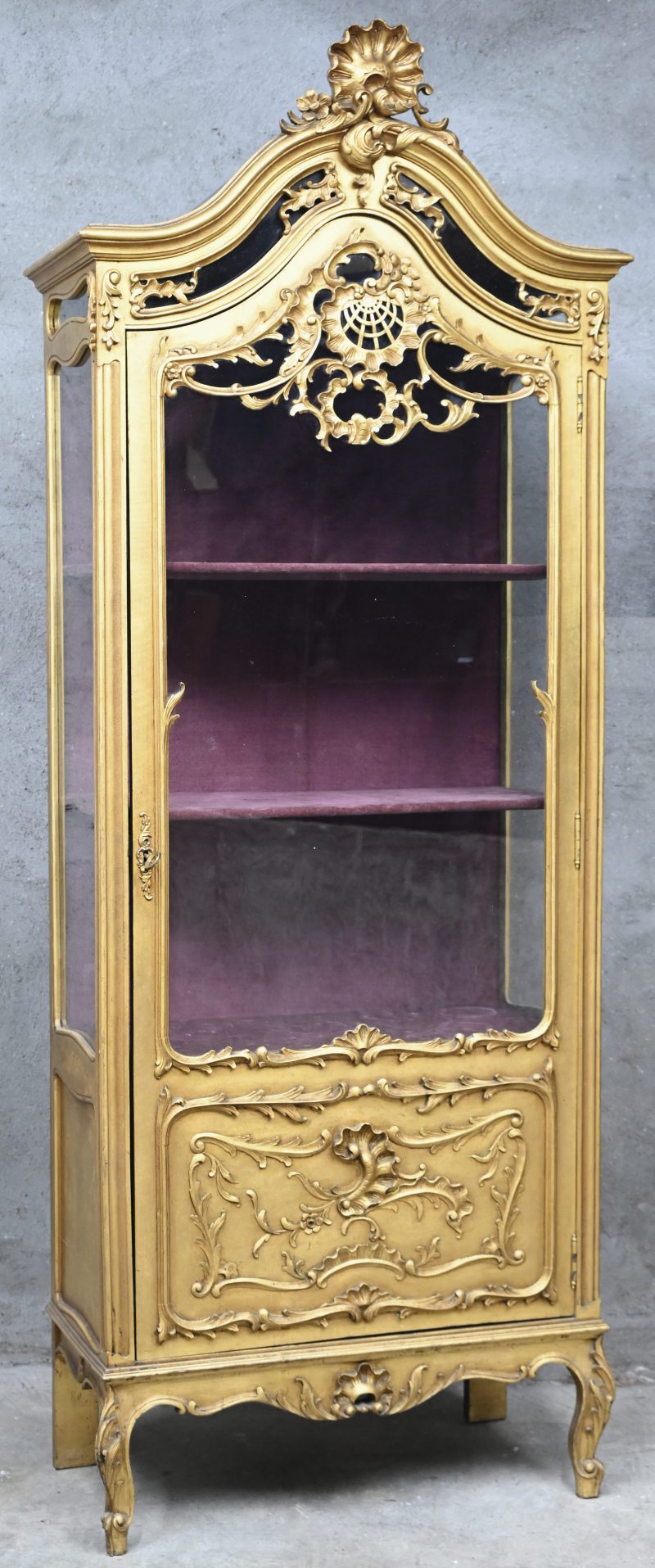 Een gesculpteerde en vergulde houten vitrinekast in Louis-XV stijl. De binnenkant is bekleed in een roze velours stof.