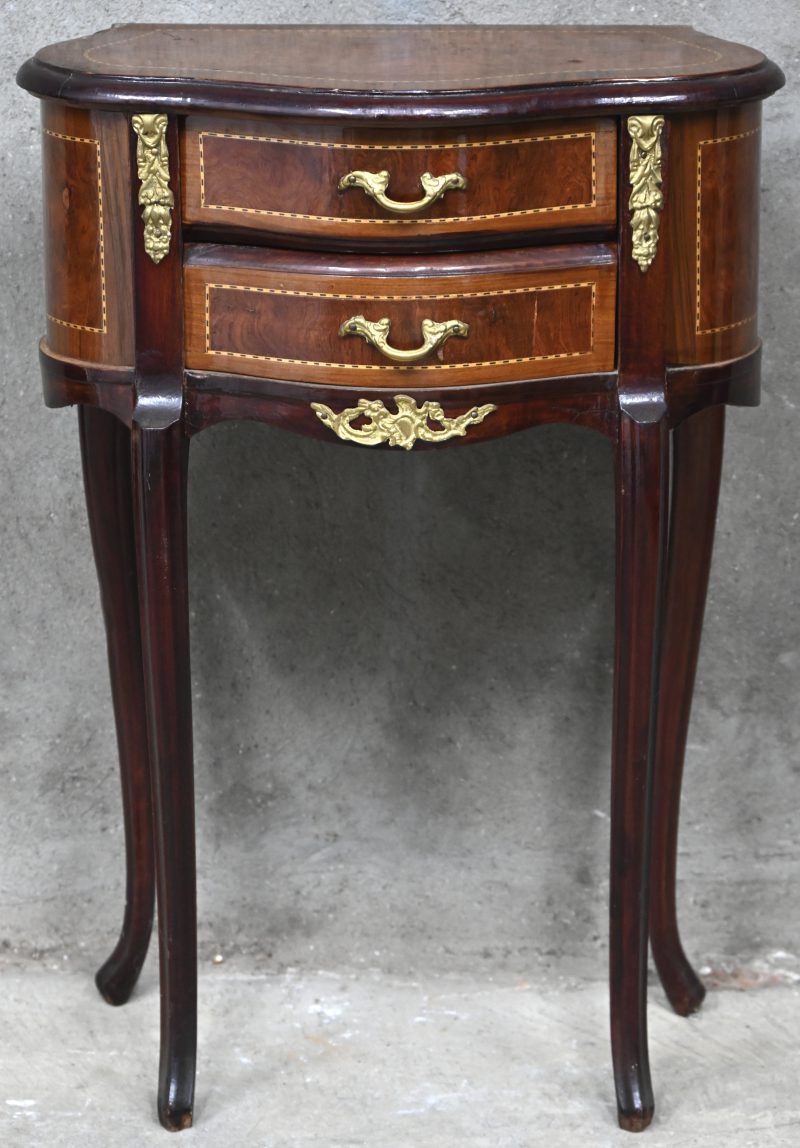 Een ladekastje in Louis-XV stijl op ranke poten, twee lasen. Met vergulde elementen en fineer inlegwerk.