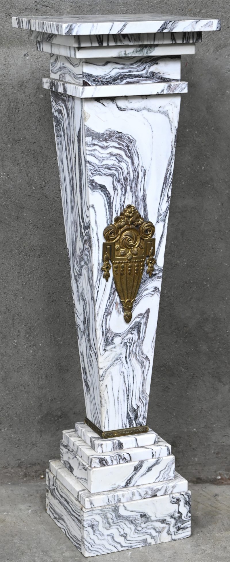Een zwaar geaderde marmeren pied-de-stal met bronzen decoratie op één kant.