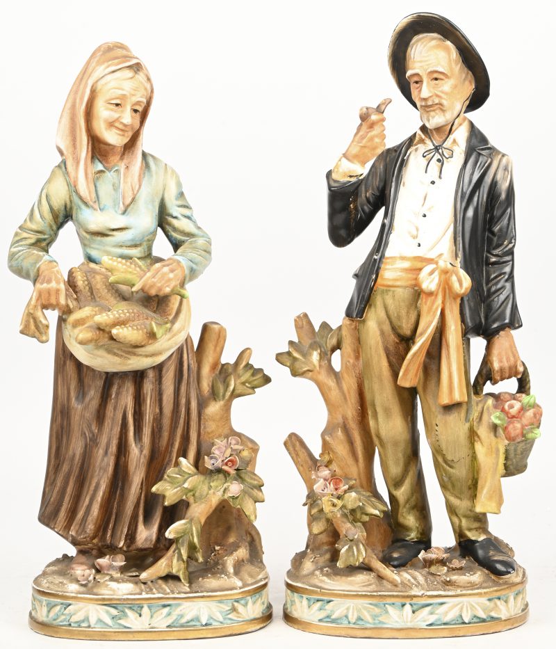 Een set van twee porseleinen beelden in de stijl van capo-di-monte, vrouw met mais en rokende man met appelmand. Made in Japan.