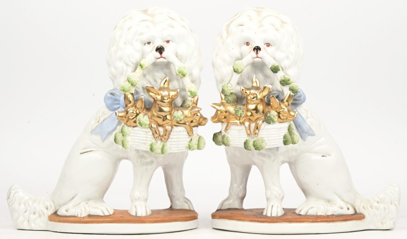 Een set van twee ‘Staffordshire’ poedels in porselein, met in hun bekje een mandje met biggetjes.