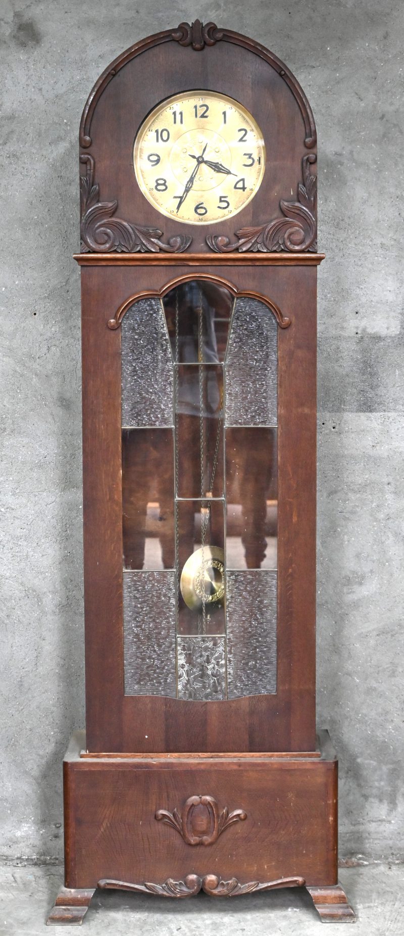 Een Art-Deco staande klok met loodglas in een eikenhouten kast.