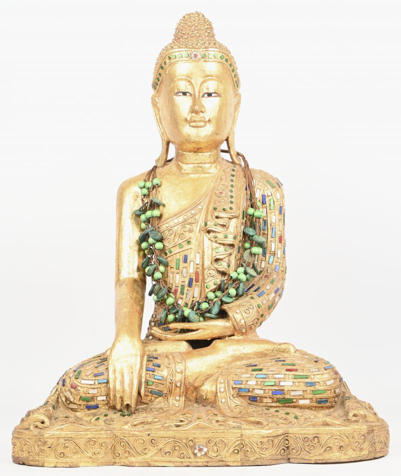 Een uit hout gesculpteerde Mandalay Boeddha met goudkleurig patina en meerkleurige pailetten.