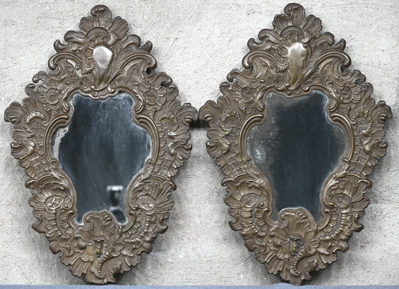 Een paar spiegels met gedreven koperen omlijsting van bewogen vorm in Lodewijk XV-stijl. XIXde eeuw.
