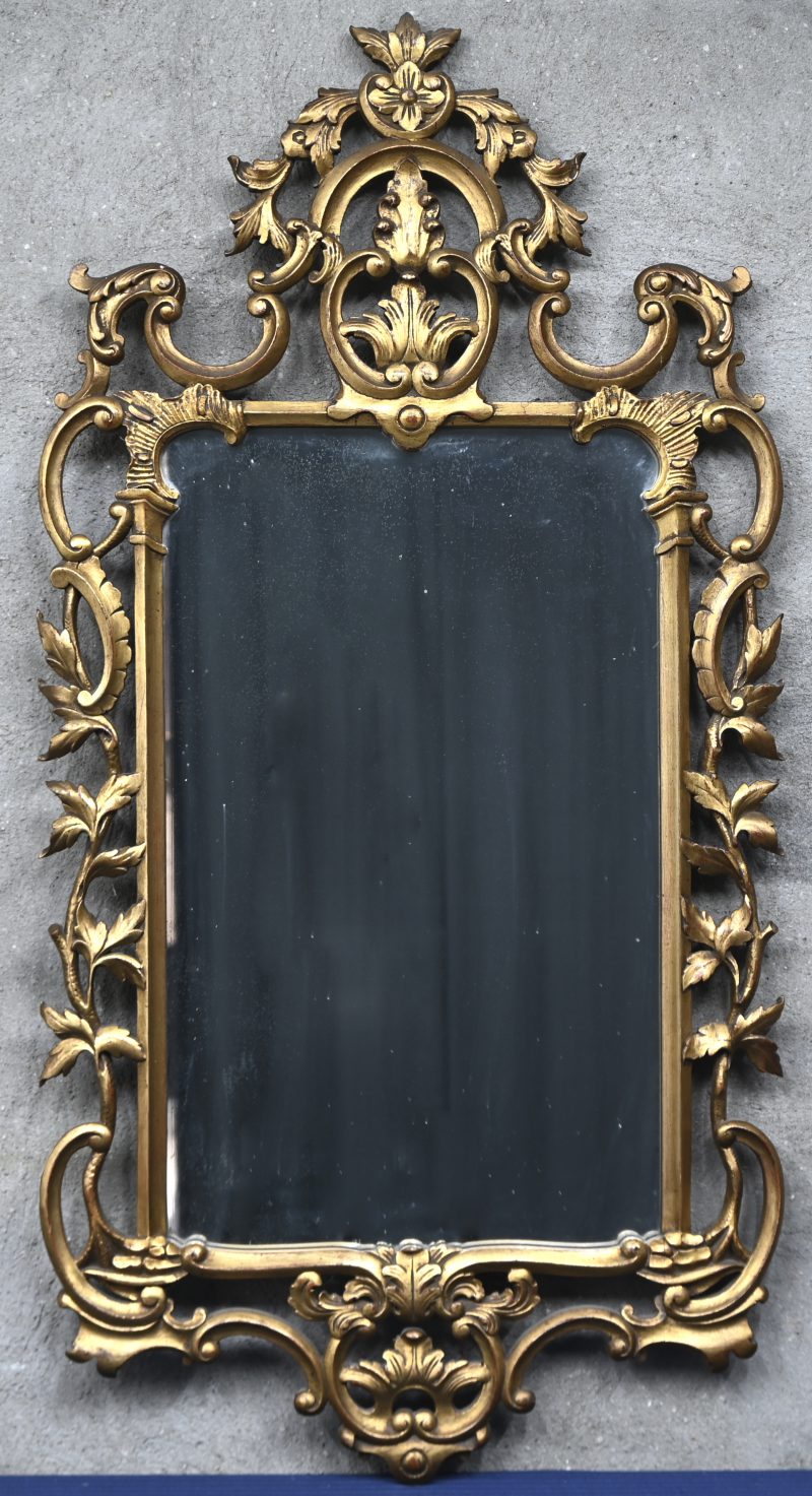 Een vergulde houten spiegel met ajourgewerkte lijst.