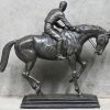 ‘Jockey te paard.’ een bronzen beeld op metalen sokkel.