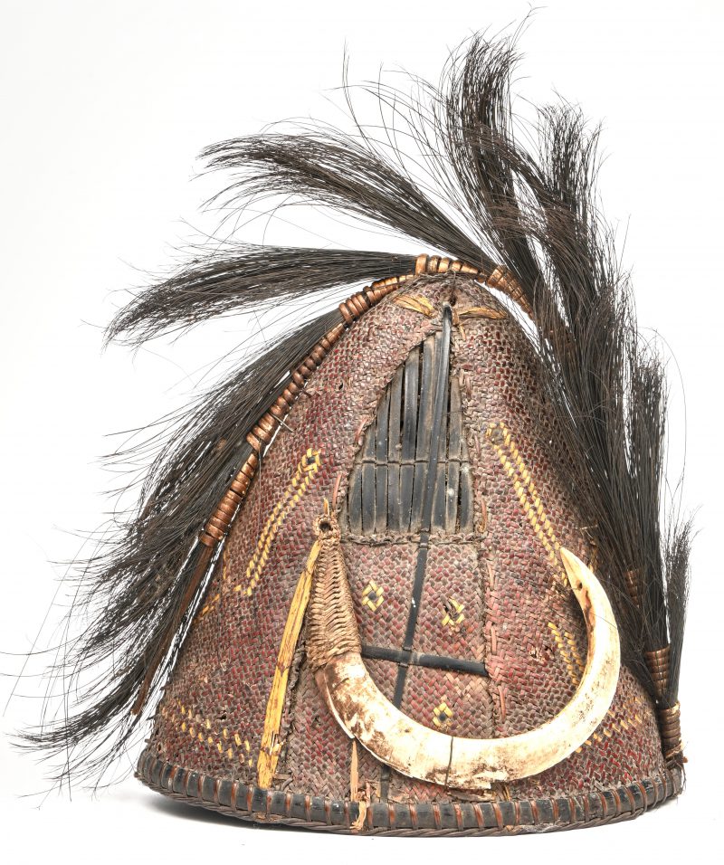 Een ceremoniële hoed van de Naga, vervaardigd uit gewoven bamboe, versierd met zwijn slagtanden. Nagaland, Indië, vroeg 20e eeuw.