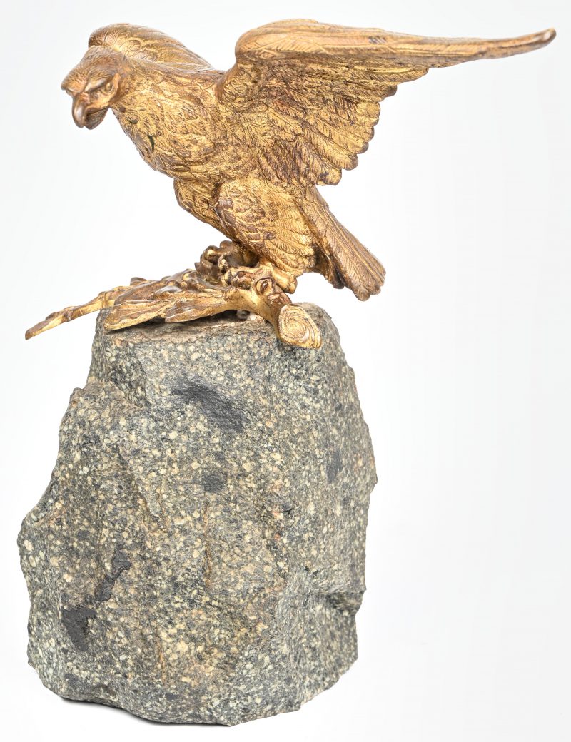 Een verguld brons gesculpteerd beeld van een adelaar op tak, gemonteerd op een kasseisteen.