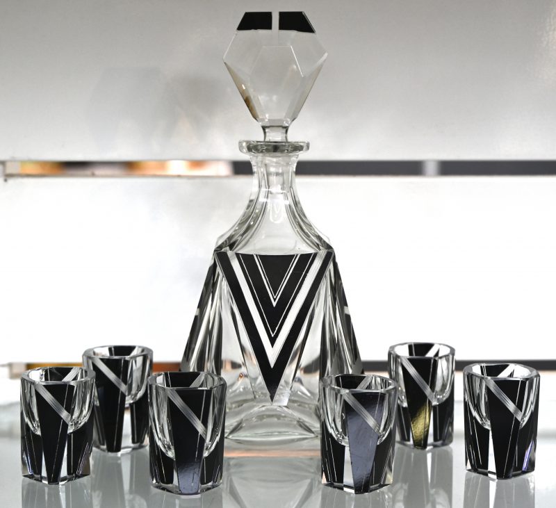 Een Art Deco Boheems kristal geslepen likeurset, bestaande uit 6 glaasjes en 1 karaf. Met geometrisch decor.
