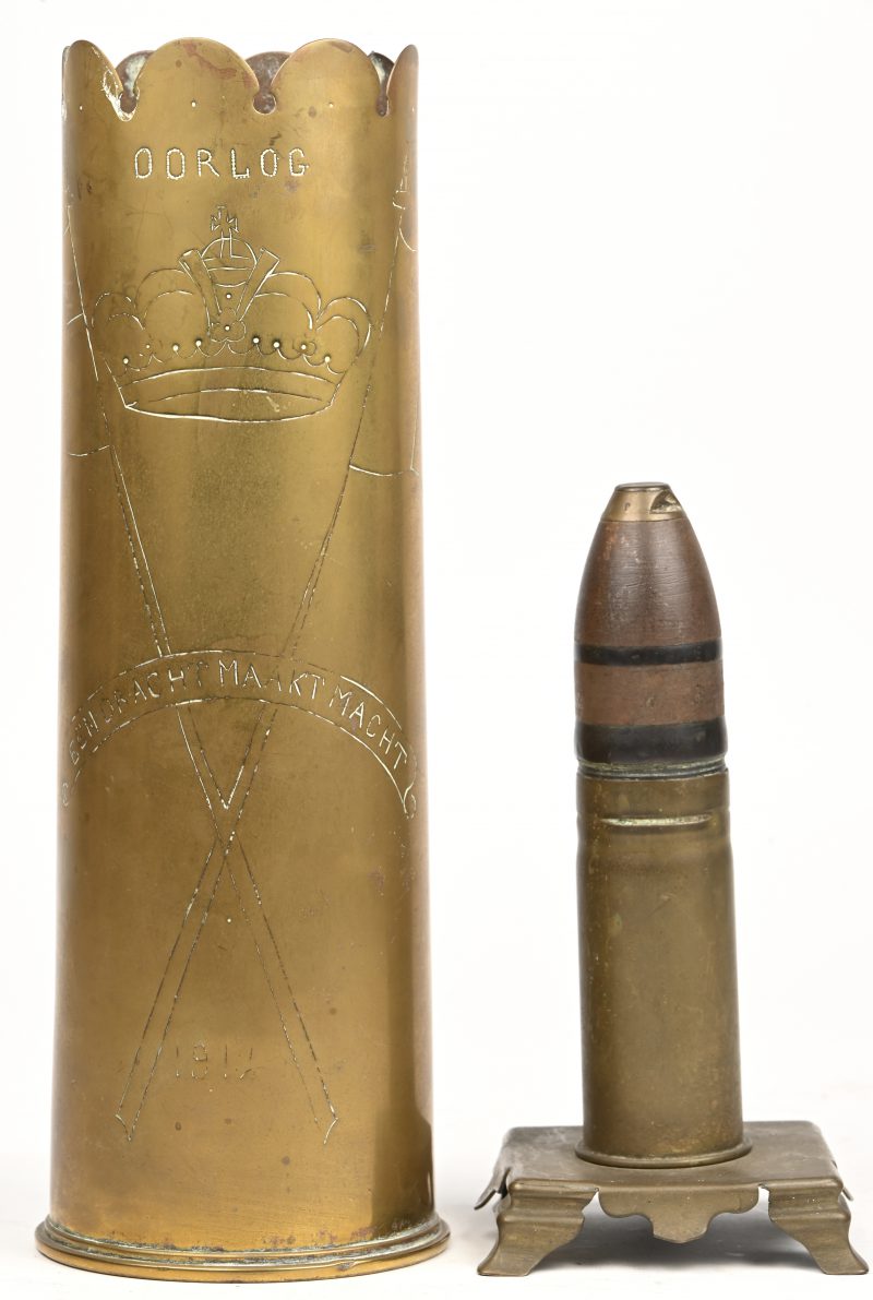 Een lot van twee souvenirs uit de 1ste wereldoorlog bestaande uit een groot kaliber kogel gemonteerd op een koperen voetstuk en een ‘trench-art’ obus met vermelding ‘OORLOG’ en ‘Eendracht Maakt Macht’, de obus is gedateerd 1917.