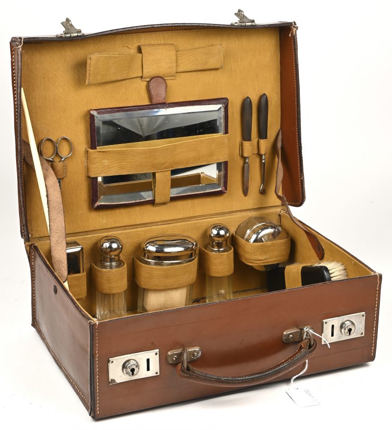 Een oud lederen valiesje met 12-delig toiletensemble. Het valiesje draagt een monogram J.F..