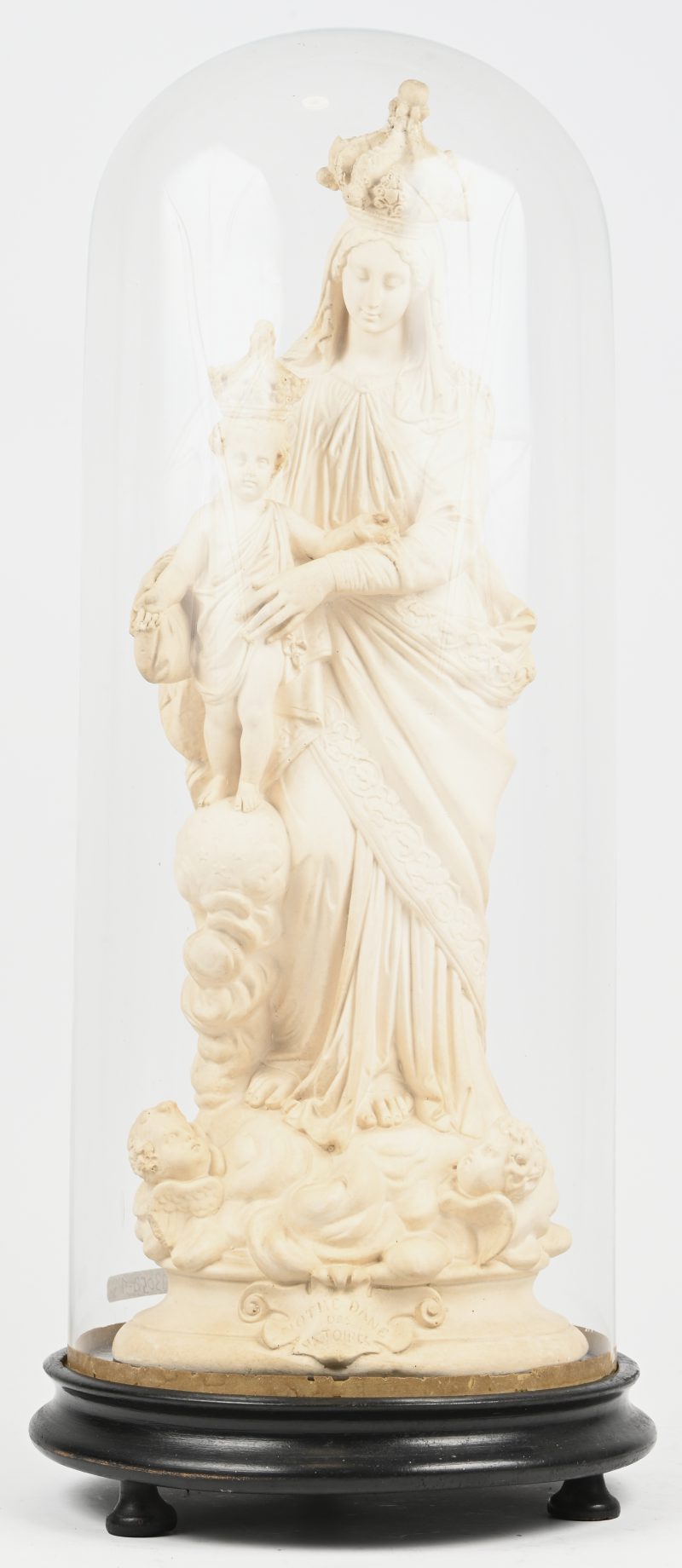 Een oude glazen stolp op houten voet met hierin een plaasteren Madonna met kind met het opschrift ‘Notre Dame des Victoires’.