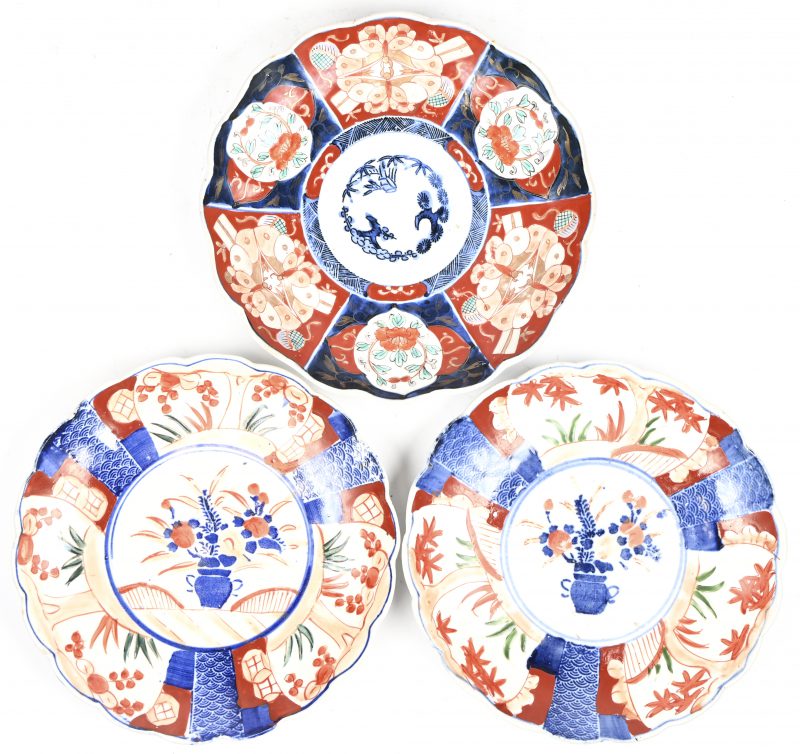 Een lot van drie Imari porseleinen borden met traditioneel decor, twee met bloemenvaas en een abstract.