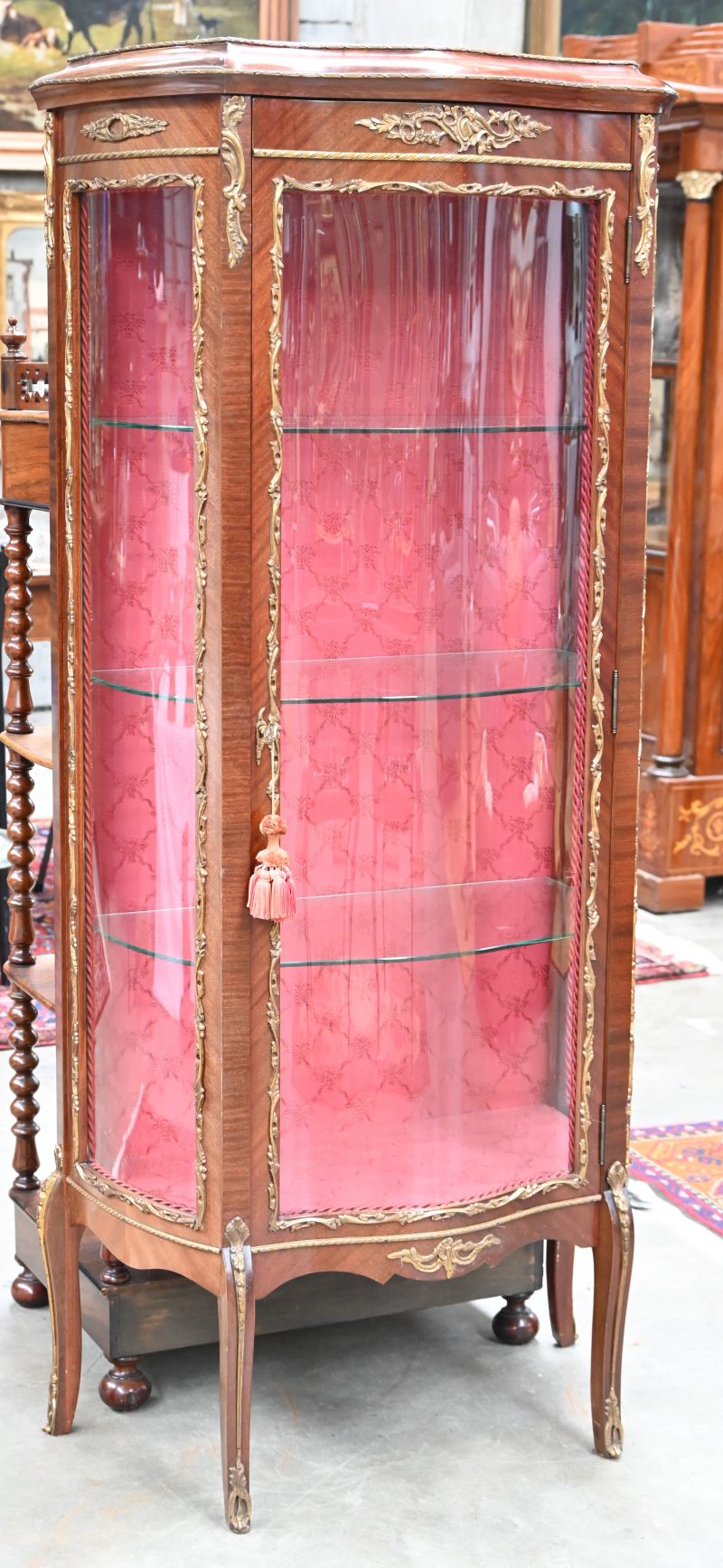 Een gefineerde vitrine met gegolfd glas, en drie niveaus. Met messingen monturen.