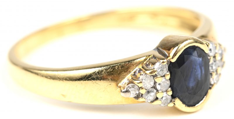 Een 18 kt geelgouden ring bezet met diamanten met een gezamenlijk gewicht van +- 0,15 ct. en een centrale saffier van +- 0,50 ct.