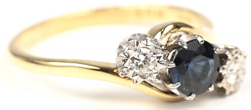 Een 18 kt wit en geelgouden ring bezet met briljanten met een gezamenlijk gewicht van +- 0,10 ct. en een centrale saffier van +- 0,65 ct.