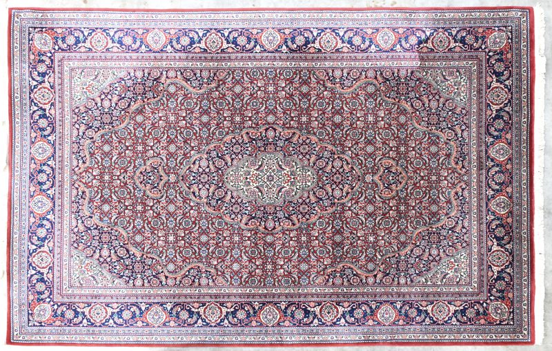 Een Perzisch handgeknoopt tapijt met centraal medaillon.