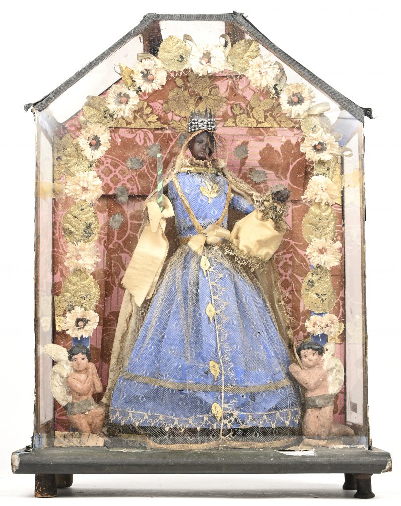 Een oude wassen zwarte Madonna met kind in een presentatievitrine. Het aangezicht van Maria is deels gesmolten.