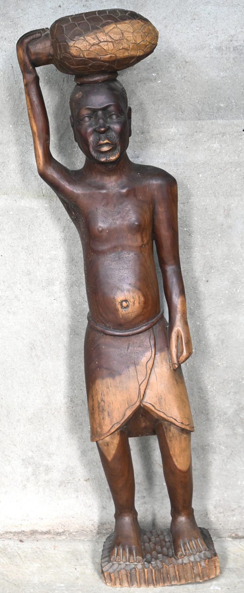 “De ananasdrager”. Een gesculpteerd massief houten beeld van een man. Afrikaans werk.