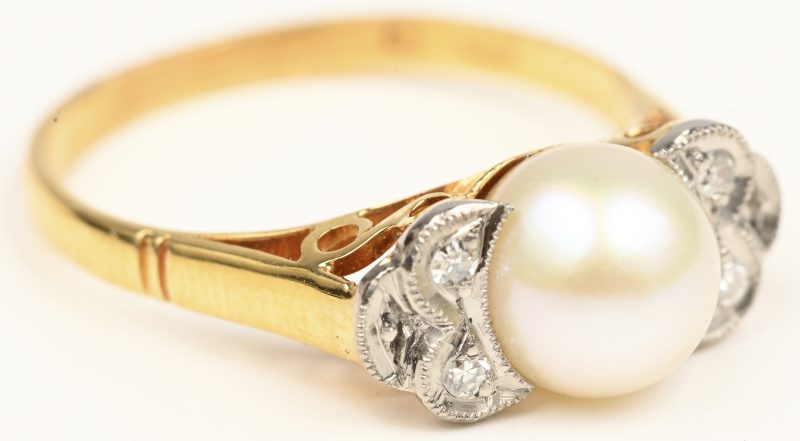 Een 18 kt wit en geelgouden ring bezet vier kleine briljanten en een parel.