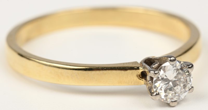 Een 18 kt wit en geelgouden ring bezet met een brilant van +- 0,30 ct.