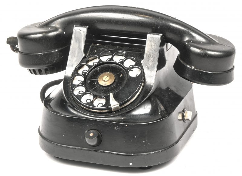Een oude bakelieten telefoon met draaischijf.