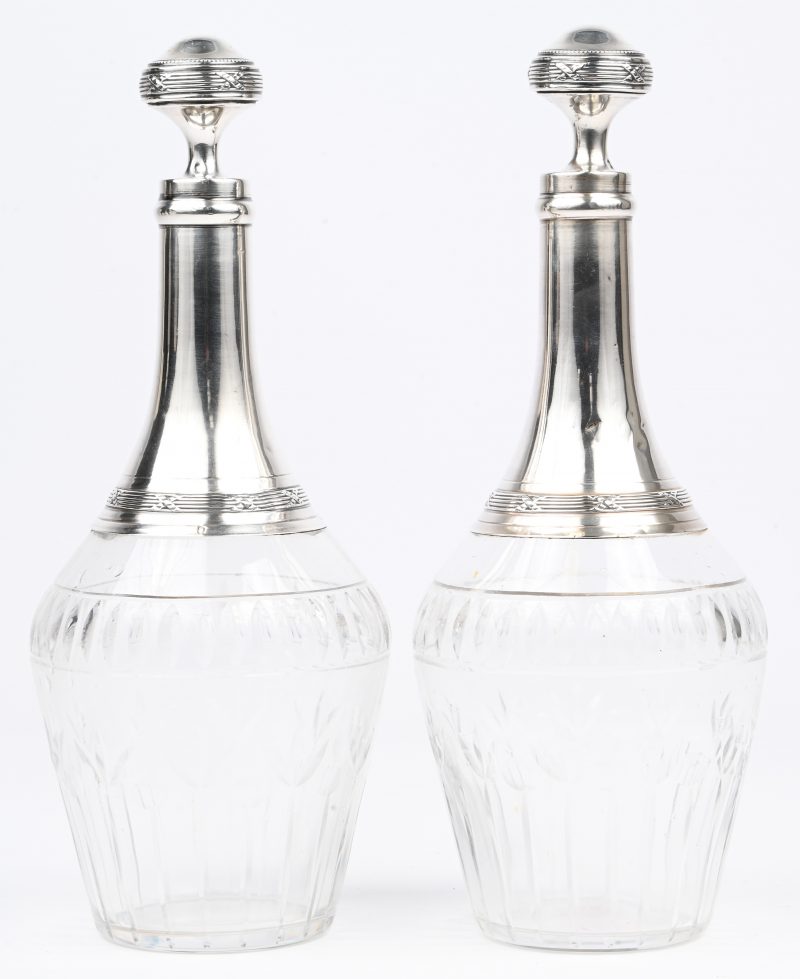 Een paar kristalglazen karaffen met zilveren hals en stop. Gemerkt Minerve, 950-1000‰, en merk zilversmid Charles Barrier, Parijs 1905-1923.