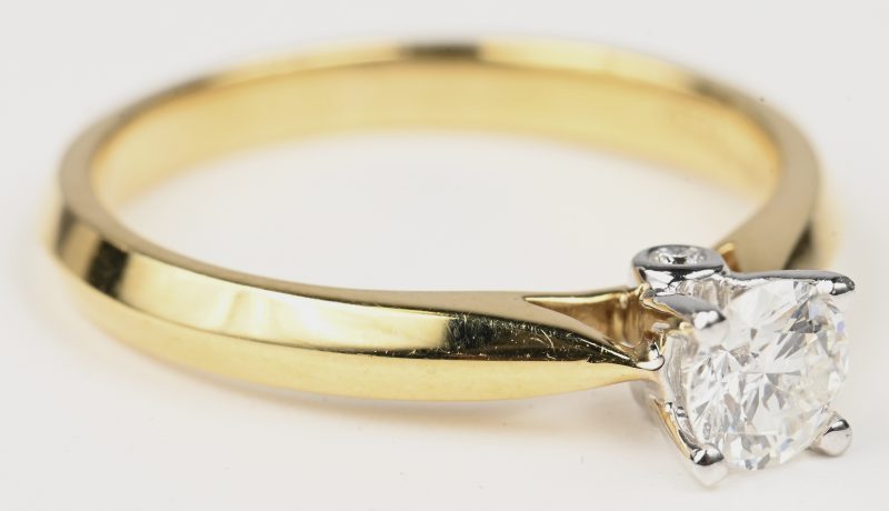Een 18 kt wit en geelgouden ring bezet met centrale briljant van 0,34 ct. en twee kleine briljantjes van 0,02 ct.