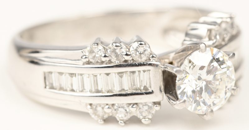 Een 18 kt witgouden ring bezet met een centrale briljant van 0,73 ct. FVS2 en diamant baguetten en briljanten met een gezamenlijk gewicht van +- 0,49 ct.