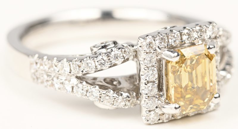 Een 18 kt witgouden ring bezet met een centrale cognackleurige diamant emerald cut SI2 van 0,72 ct. en briljanten met een gezamenlijk gewicht van +- 1,26 ct.
