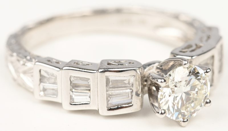 Een 18 kt witgouden ring bezet met een centrale briljant van 0,72 ct. en baguetten met een gezamenlijk gewicht van +- 0,42 ct.