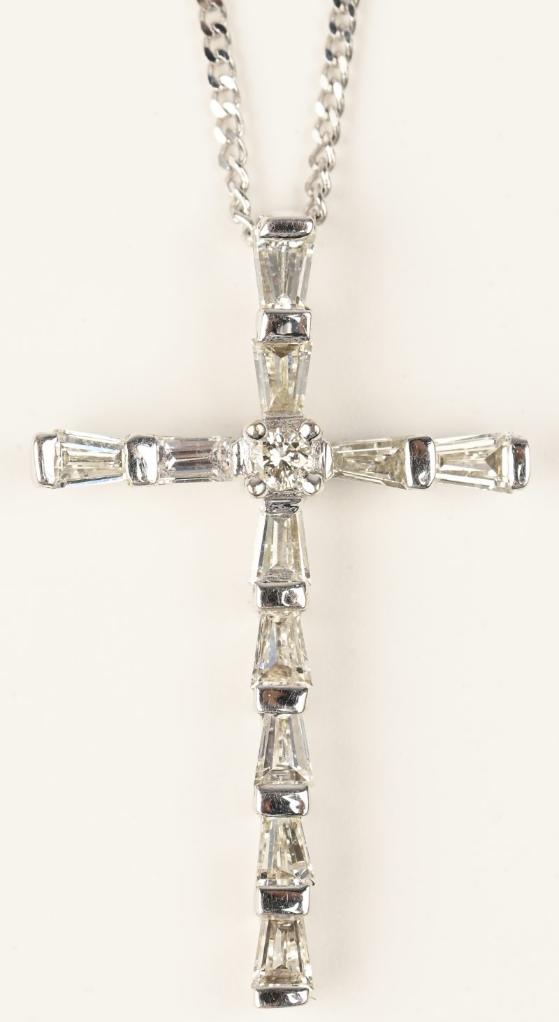 Een 18 kt witgouden ketting met hanger in de vorm van een kruis bezet met baguetten en één briljant met een gezamenlijk gewicht van +- 0,68 ct.
