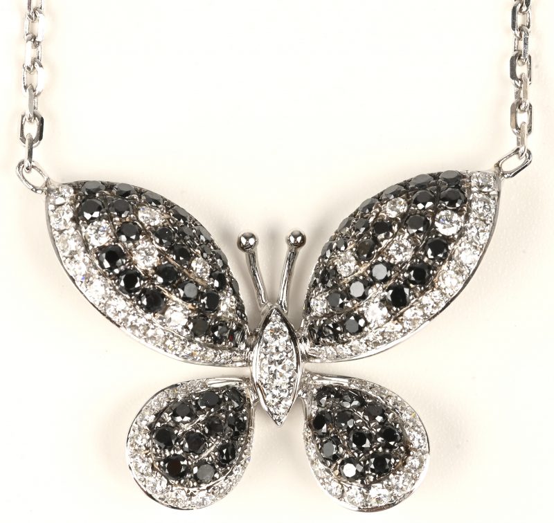 Een 18 kt witgouden ketting met hanger in de vorm van een vlinder bezet met witte en zwarte briljanten met een gezamenlijk gewicht van +- 2,62 ct.