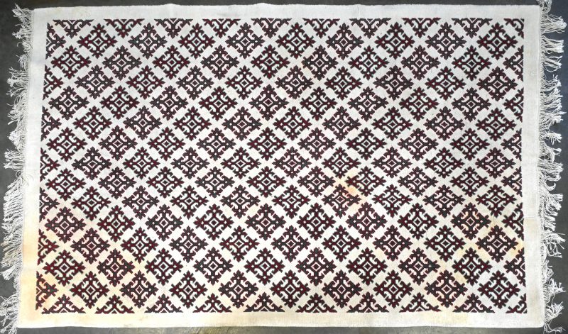 Een Tunesisch handgeknoopt wollen tapijt met geometrisch motief.