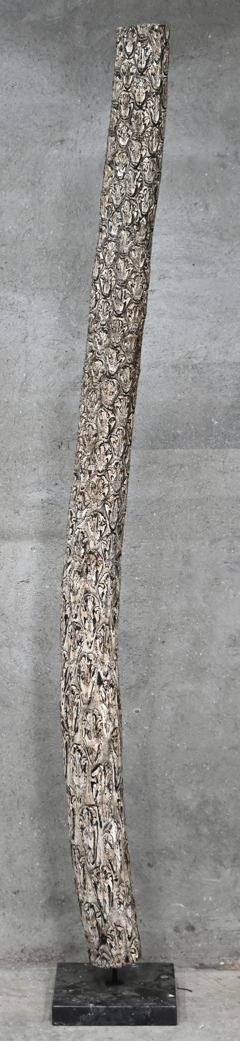 Een boomstronk in tropisch hout op een marmeren sokkel gemonteerd.