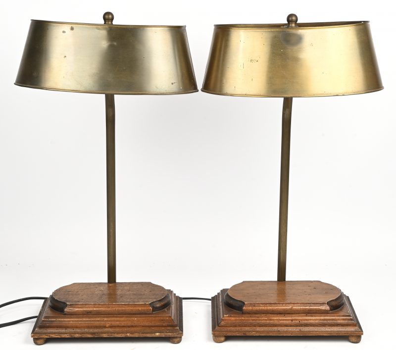 Twee vintage bureaulampen met messing kappen en houten voetstukken, mogelijk uit het midden van de 20e eeuw.