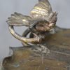 Een koperen bijzettafeltje, het tablet in de vorm van een gegraveerd blad met een kever en een vogel in reliëf. OP een centrale driepoot in bamboe-imitatie versierd met een touwmotief. Omstreeks 1900.